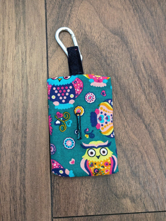 Upcycled Refillable Dog Poo Bag Holder – Clip-on Dispenser, Eco-Friendly & Handmade in the UK from recycled fabric. A dog walking essential in a bright multicoloured owl print on a darker teal background complete with button hole and metal clip.