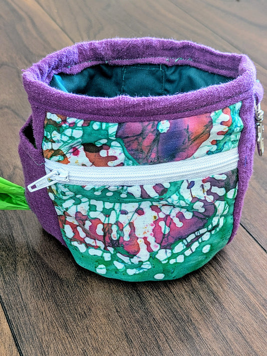 Purple and green dog treat pouch made from upcycled fabric. Has wipeable lining, zip front pocket, poo bag holder, clip for keys and a belt loop attachment for hands free training.