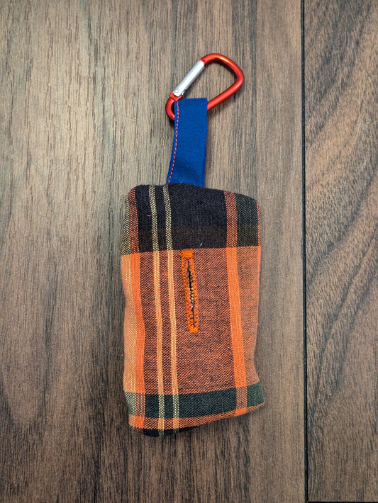 An eco friendly orange and navy checked dog waste bag dispenser made from a preloved shirt. Complete with a bright blue loop and red carabiner clip.